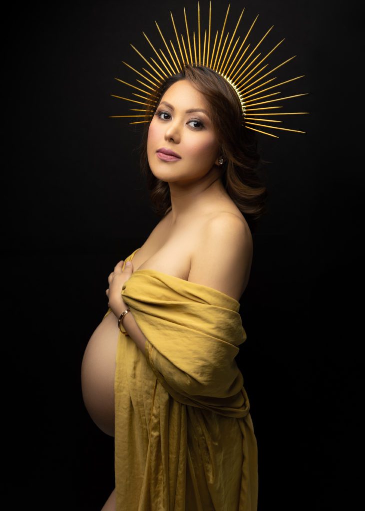 Beautiful Pregnancy photo of mom to be wearing a gold silk fabric and gold crown