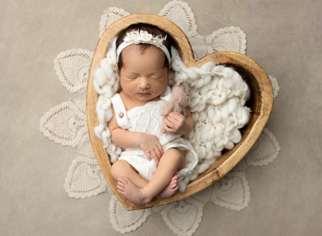 Baby girl Emersyn in white, laying in heart prop